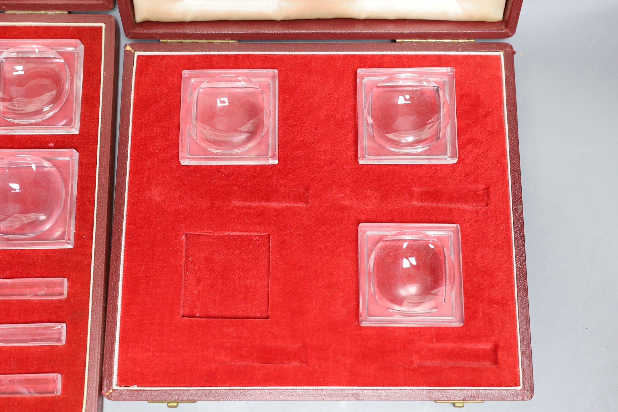 In incomplete set of Baccarat butter dishes together with a complete set of Baccarat butter dishes and knives, both in Asprey fitted cases